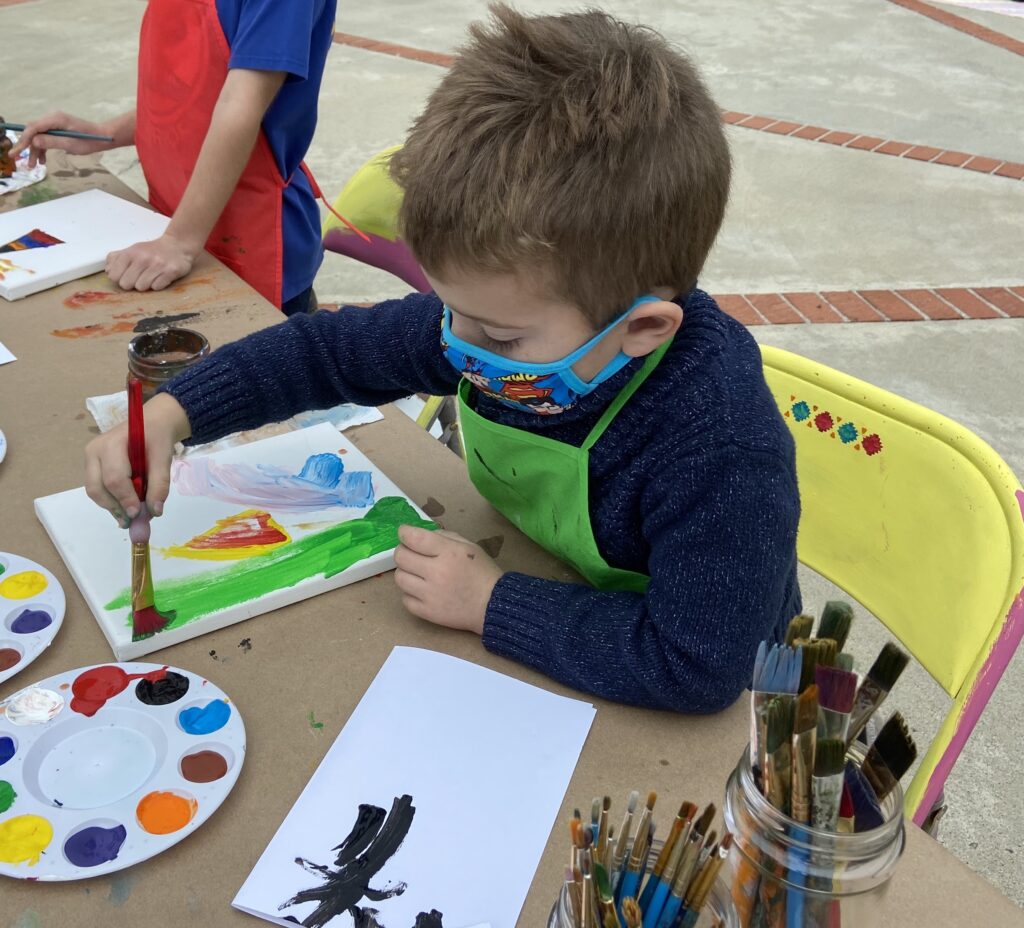 child painting with a paintbrush and canvas, acrylic paint