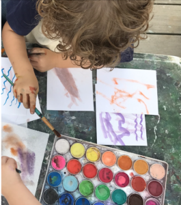 early childhood student painting with paint and a paintbrush