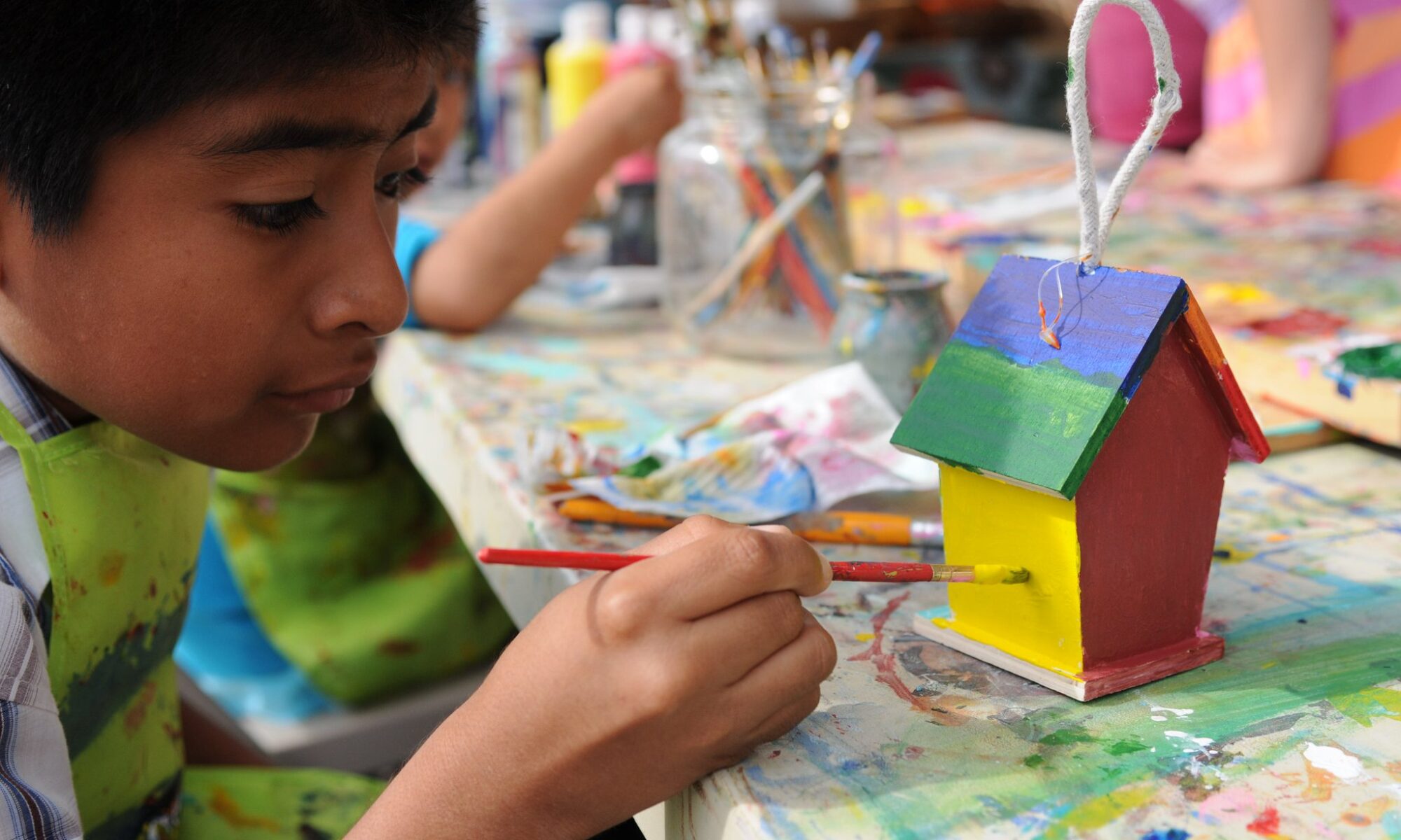 summer art camp activity, boy painting a bird house with acrylic paint